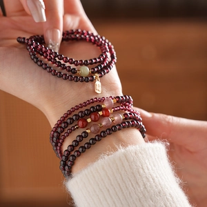 Detailed view of garnet bead bracelet with jade accents and gold fortune pendant charm