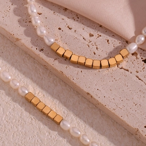 Macro shot of freshwater pearls and golden square beads on a neutral stone surface