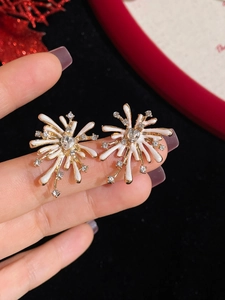 Detailed close-up of fireworks-shaped earrings with rhinestones and white enamel finish