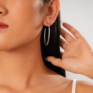 Close-up of minimalist silver circular hoop earring on model with polished metal finish