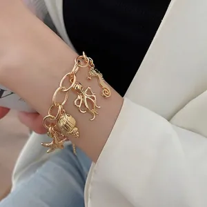 Golden chain bracelet with ocean charms like seahorse and starfish worn on a wrist