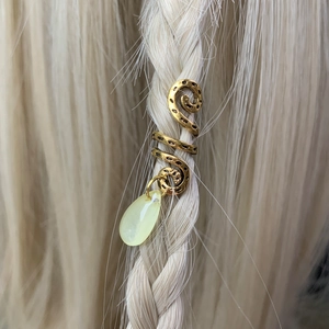 Detail of golden dreadlock hair cuff with a yellow teardrop charm on braided hair