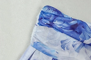 Detailed close-up of blue floral print on sheer mesh fabric with pleated waist texture