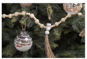 Detail of Christmas snowman wood bead garland with rustic tassels on green pine tree branch