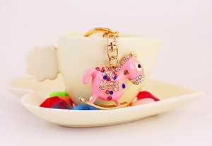 Detail of pink rocking horse keychain with sparkling crystals and golden metal accents