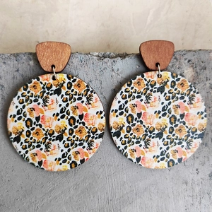 Close-up of bohemian leopard print earrings on a minimalist grey concrete background