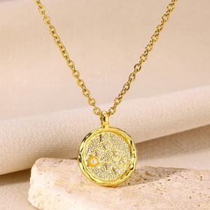Close-up of a gold medallion necklace with tiny pearls and sparkling zircon stones