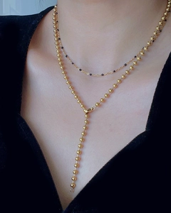 Close-up of a double-layered gold bead necklace set worn on a model in a v-neck style