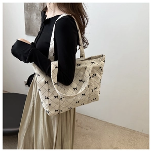 Detail of cream corduroy tote bag featuring black bow patterns and quilted diamond stitching