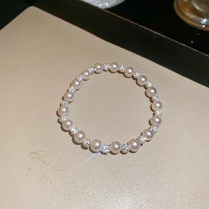 Close-up of elegant pearl and rhinestone beaded bracelet on a beige jewelry display tray