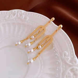 Détail macro de boucles d'oreilles perles dorées sur une assiette en céramique décorative