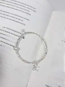 Macro shot of S925 silver flower charm and freshwater pearls on an open book