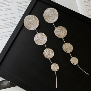 Silver drop earrings with tiered circular metal discs and intricate spiral texture finish