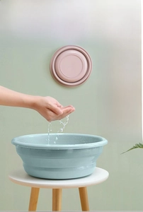 Detail of light blue collapsible washbasin fully expanded with water on a wooden stool
