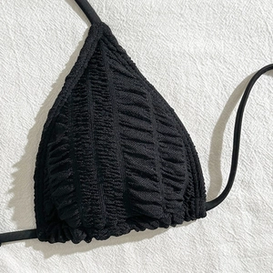 Detailed close-up of black triangle bikini top with textured seersucker fabric and ties