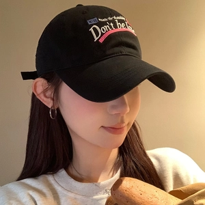Retro black baseball cap with letter embroidery worn by a model in soft lighting