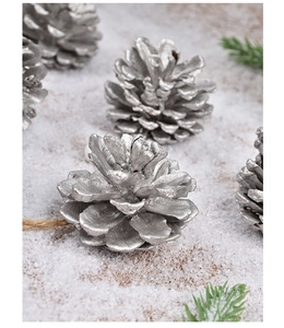 Detail of silver pine cone ornaments on a snowy background with rustic hemp rope and needles