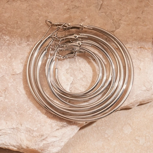 Polished silver concentric round hoop earrings set in four sizes on marble surface