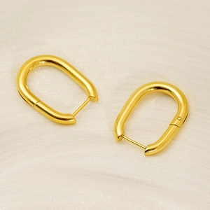 Minimalist 18k gold plated stainless steel U-shaped hoop earrings on soft beige fabric