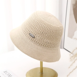 Breathable cream knit bucket hat for women with elegant mesh pattern and metal emblem