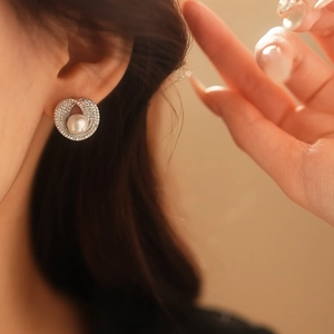 Gros plan sur une boucle d'oreille spirale en argent avec perle ronde, bijou porté à l'oreille
