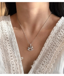 Close-up of a silver rocking horse pendant with cubic zirconia on a female neck