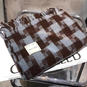 Detail of brown and blue plaid scarf with fringes and minimalist brand label on a magazine