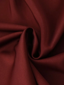 Detail of burgundy satin midi dress fabric showing soft texture and elegant draped knot
