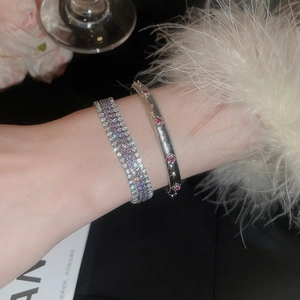 Nahaufnahme eines eleganten mehrreihigen Zirkonia-Armbands und Rubin-Armreifs am Handgelenk