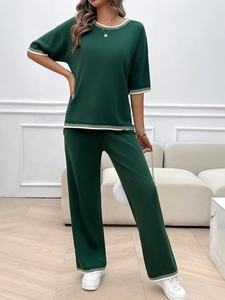 Détail d'un ensemble vert foncé avec des liserés beiges contrastés sur manches et pantalon
