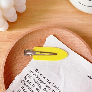 Close-up of a yellow oval hair clip on a wooden tray with aesthetic decorative background