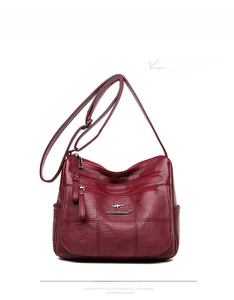 Detail view of dark red multi-zipper handbag with litchi texture and adjustable strap
