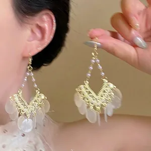 Detail of bohemian tassel earrings with woven gold wire, pearls and shell discs