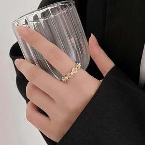 Detail of elegant leaf ring with white pearls and zircons held on a glass
