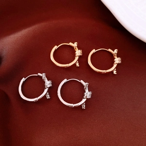 Close-up of 18k gold plated hoop earrings with zircon knots on red silk fabric