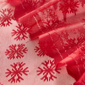 Macro shot of red lace fabric with intricate snowflake knit patterns and mesh structure