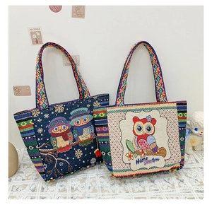 Close-up of ethnic embroidered tote bags in navy and cream with owl pattern detail