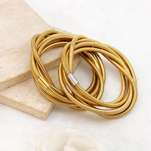 Detailed macro of golden multi-layer spring bangles with textured finish and metal clasps