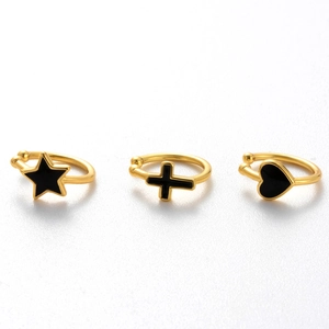 Golden cartilage ear cuffs set with black enamel star cross and heart charms on white background