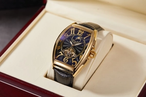 Macro detail of tonneau mechanical watch with gold case and skeleton tourbillon dial