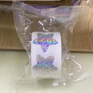 Macro shot of holographic star-shaped sticker roll in clear self-adhesive packaging