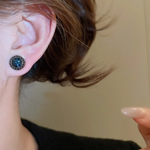 Detail of vintage silver needle stud earrings with deep blue stone and black pavé edges