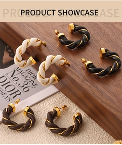 Detail of British style twisted C-shape earrings featuring leather and copper accents