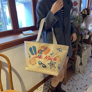 Detailed view of beige linen tote bag with beach motifs and Santa Marta text