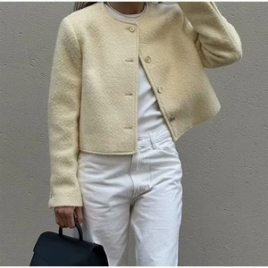 Dettaglio dell'elegante giacca in tweed color crema con classico scollo rotondo e tessuto
