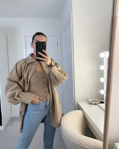 Selfie miroir détaillé d'une veste oversize en laine camel avec un gilet en maille beige