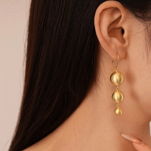 Chic gold-plated triple ball drop earrings with matte finish worn by a female model
