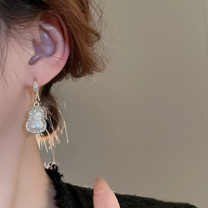 Elegant gold gourd earrings with pearls and crystals worn on ear for stylish look