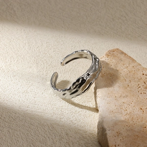 Macro detail of silver open ring featuring irregular lava texture on organic curved metal