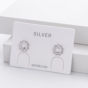 Macro shot of silver sunburst stud earrings on a white geometric display stand